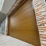 Puerta Reforzada 🚪 Puerta seccional automática Duramax color roble miel instalada en cochera moderna