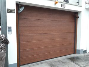 Puerta Reforzada 🚪 Puerta seccional automática color roble texturado instalada en cochera residencial moderna